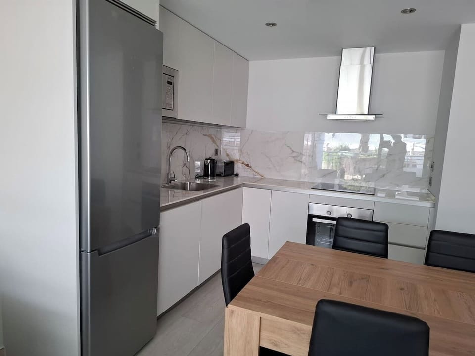 Fully-equipped modern kitchen with high-end integrated appliances including an induction hob, oven, and dishwasher. Perfect for home-cooked meals enjoyed at the adjacent 6-seater oak dining table.