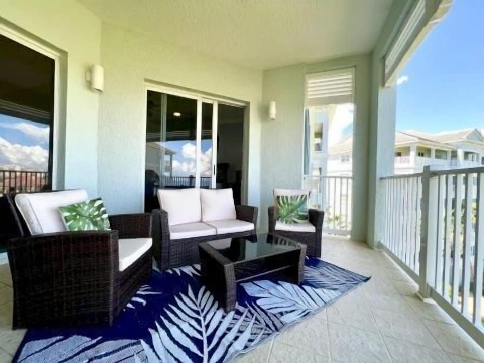 Private balcony with two chairs and a table overlooking the ocean and blue sky