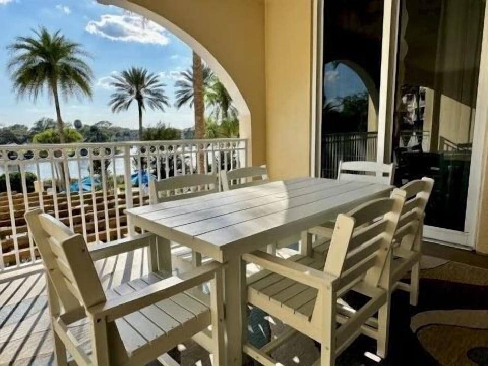 Outdoor dining set on the balcony overlooking the community pool and palm trees