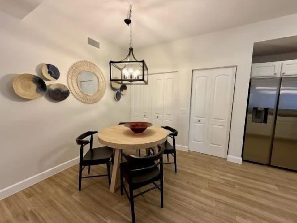 Dining nook with a round wooden table and four black chairs beneath wall art