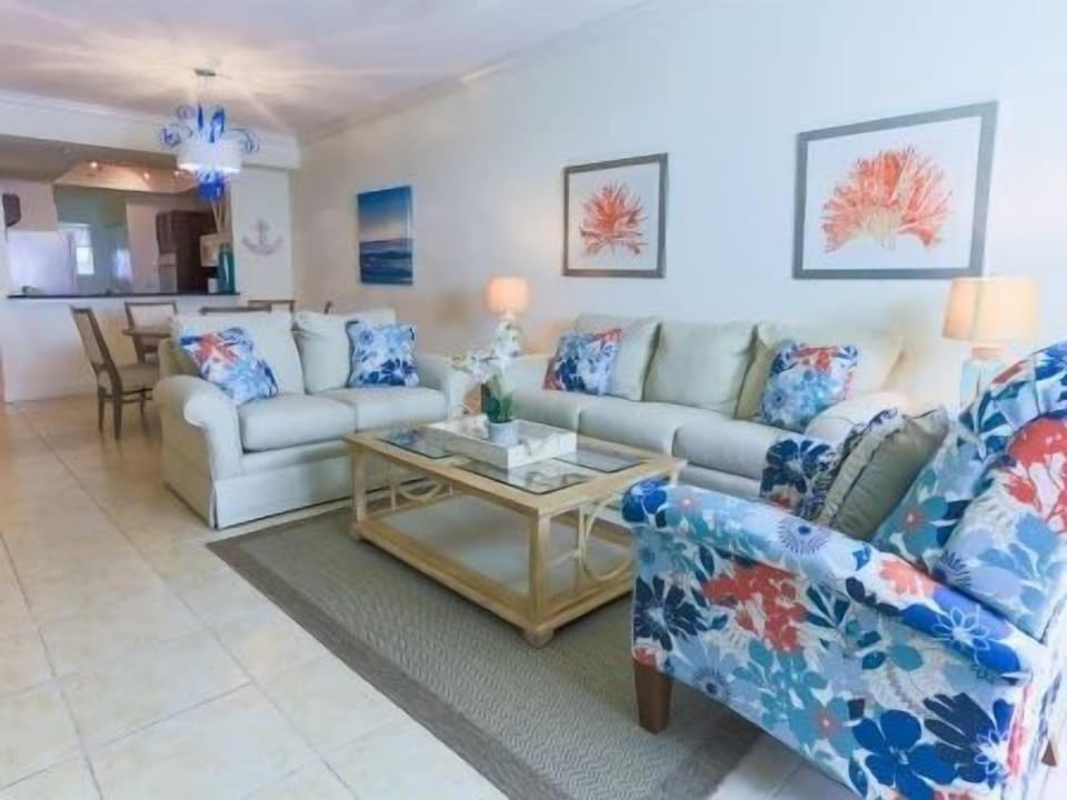 Living room with two floral-patterned sofas, a wooden coffee table, and coral artwork on the walls
