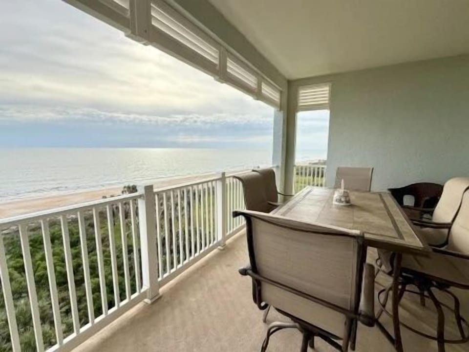 Private balcony with outdoor seating overlooking the ocean and golf course horizon