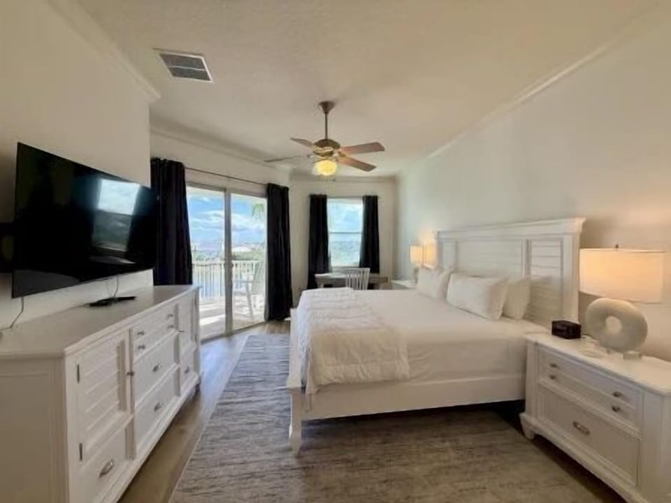 King master bedroom with white linens, lake views, and direct access to the private balcony