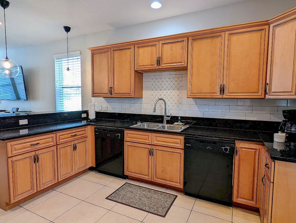 Kitchen island with bar stool seating, white cabinetry, and bright windows bringing in natural light