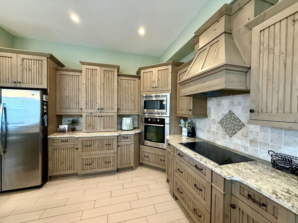 Gourmet kitchen with beadboard cabinetry, granite counters, and full-sized modern appliances