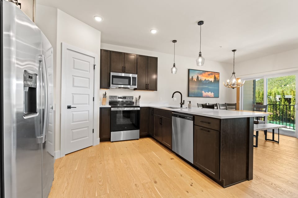 Prepare your favorite meals in this modern, well-equipped kitchen featuring sleek stainless steel appliances, elegant pendant lighting, and a bright open layout that flows into your dining space.