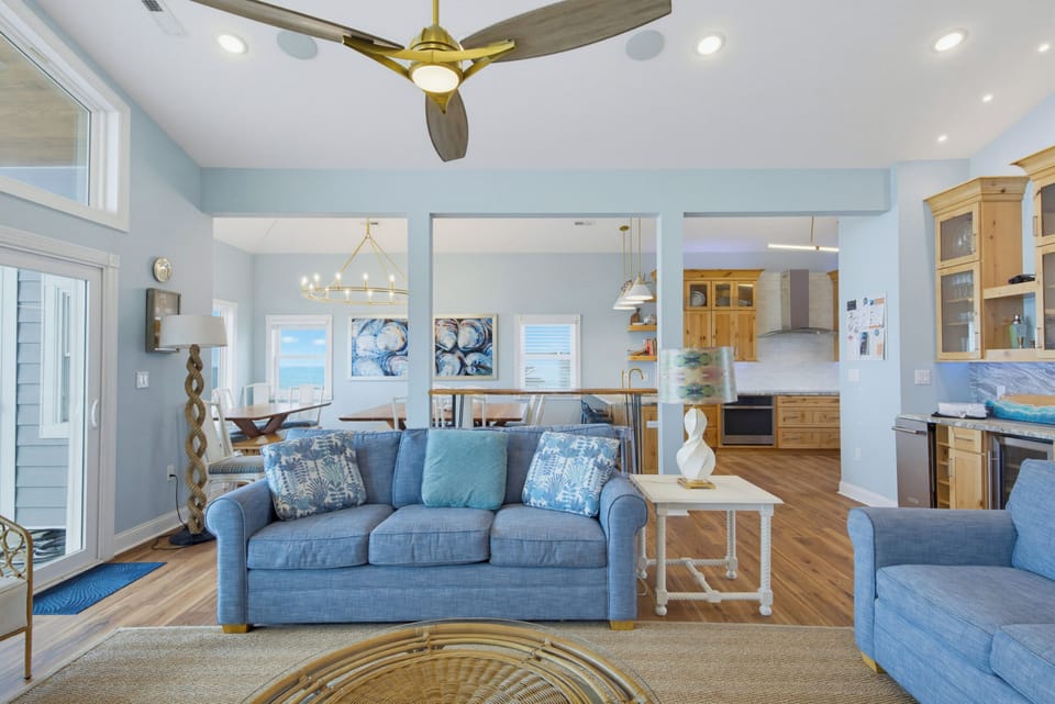 Settle into coastal comfort in your open living space, where soothing blue tones and natural light invite relaxation. The breezy layout flows effortlessly from lounge to dining to kitchen.