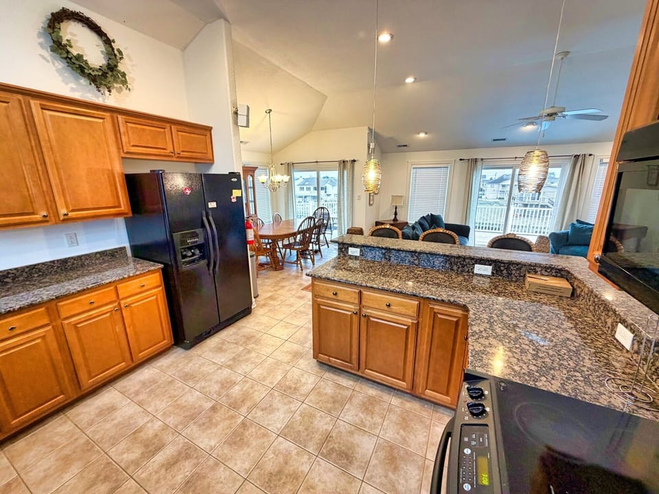 Open kitchen with granite bar, vaulted ceilings & bright deck views
