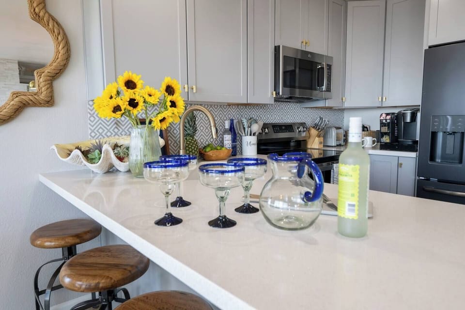 A modern, fully stocked kitchen featuring organic spices, olive oil, balsamic, and a premium coffee/tea bar with creamers and cocoa. Thoughtful extras like to-go cups, foil, and plastic bags are all provided for an effortless stay.