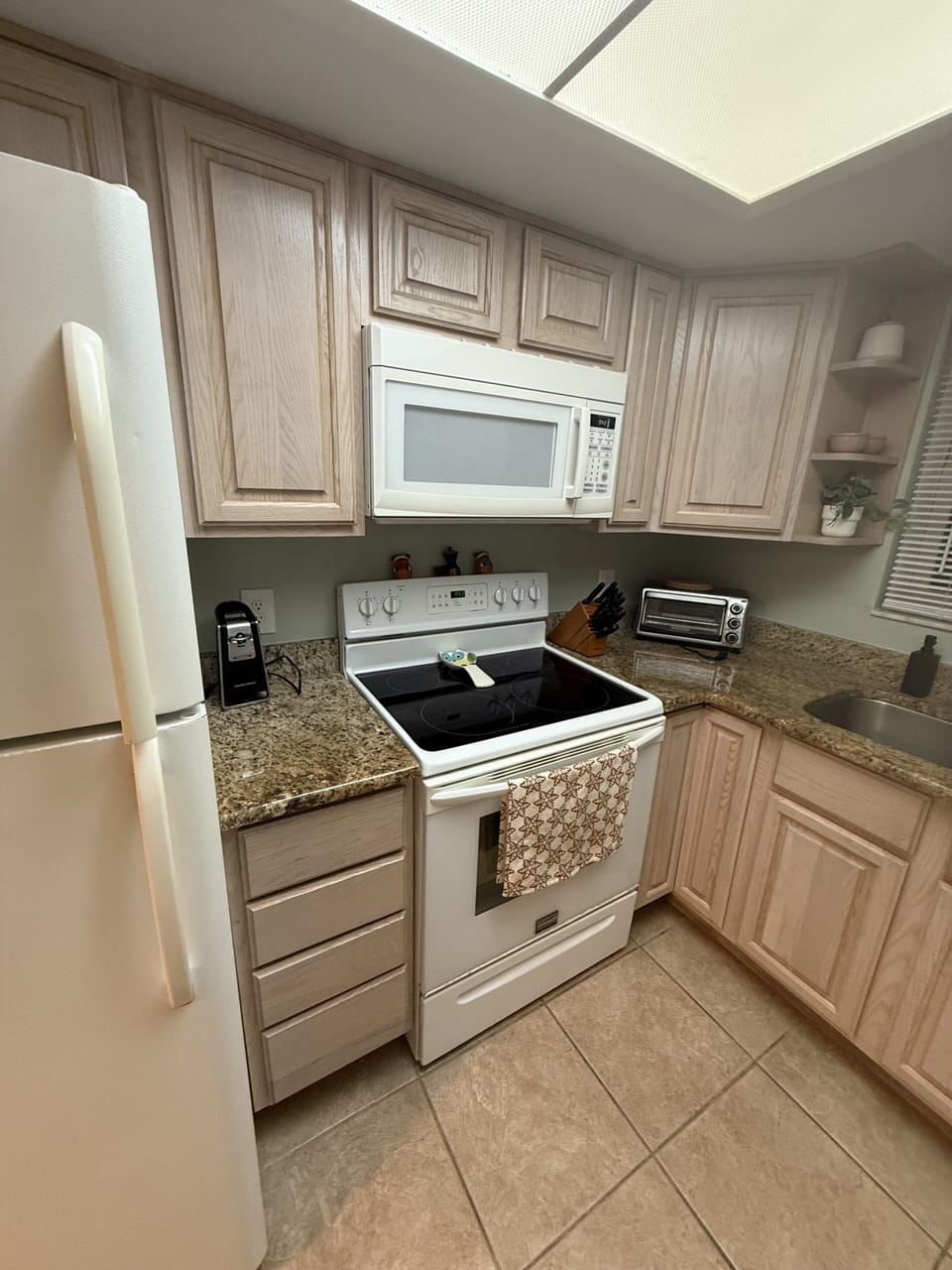 Bright full kitchen with granite counters, coffee maker, and ample prep space