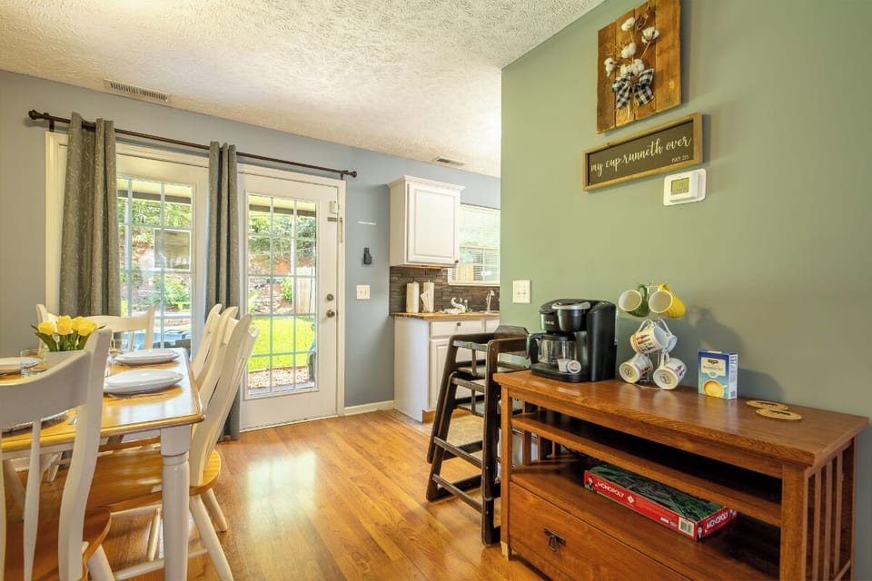 Gather around the sunny dining table with fresh coffee brewing—your mornings here start with warm light and a peaceful view of the garden beyond the door.