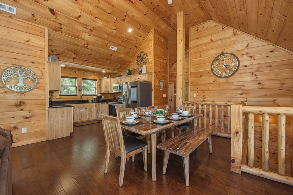 Gather around the rustic dining table in this warm wood cabin, where the open kitchen invites you to cook and share meals together beneath soaring vaulted ceilings.