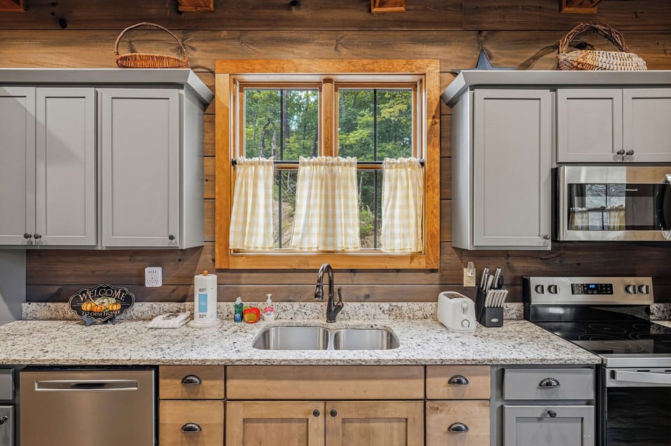 Your fully-equipped kitchen blends rustic charm with modern convenience—cook your favorite meals while gazing at the peaceful woods through charming café curtains.