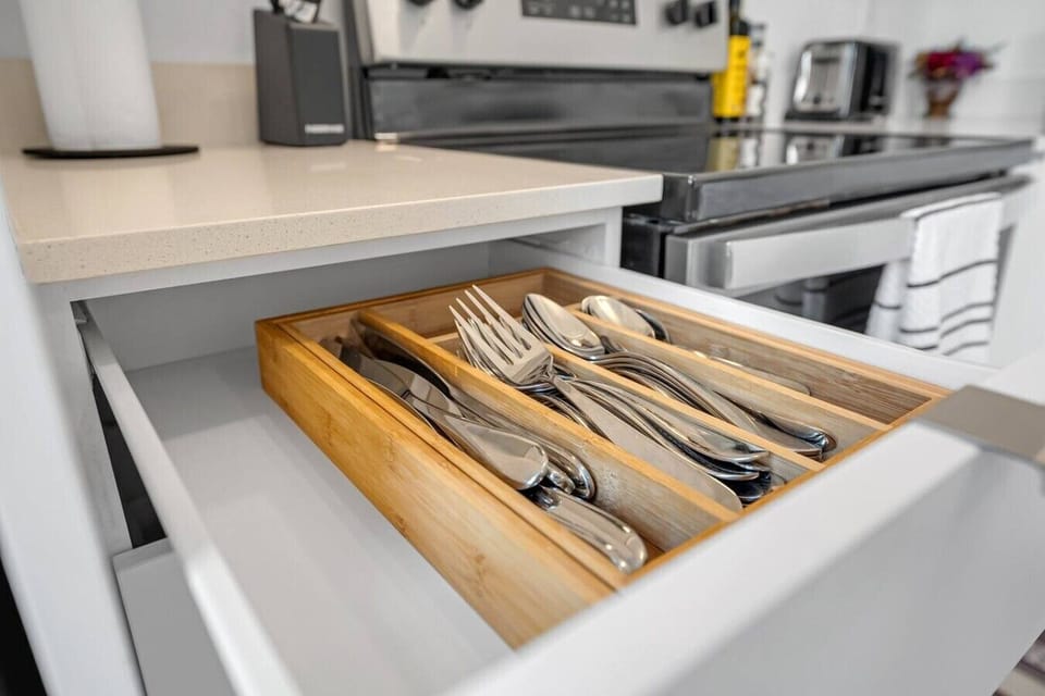 A close-up view of a wooden organizer drawer neatly stocked with polished silverware and utensils—handy for quickly grabbing what you need to set the dining table for a feast.