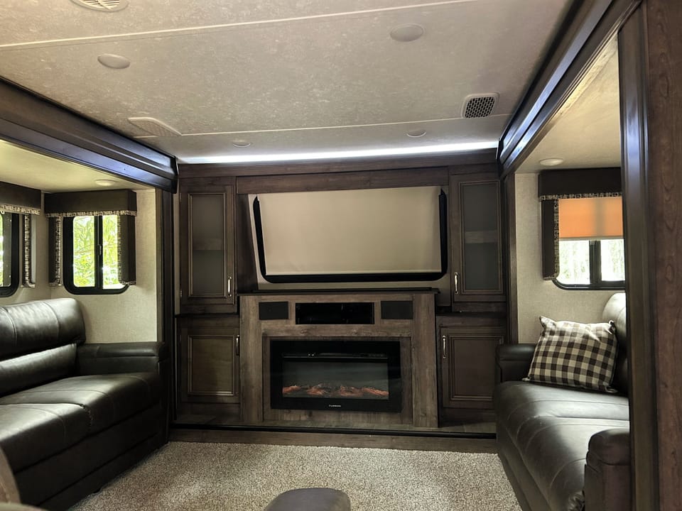 Living room.  Both couches for out for beds, large tv rises above the fireplace.