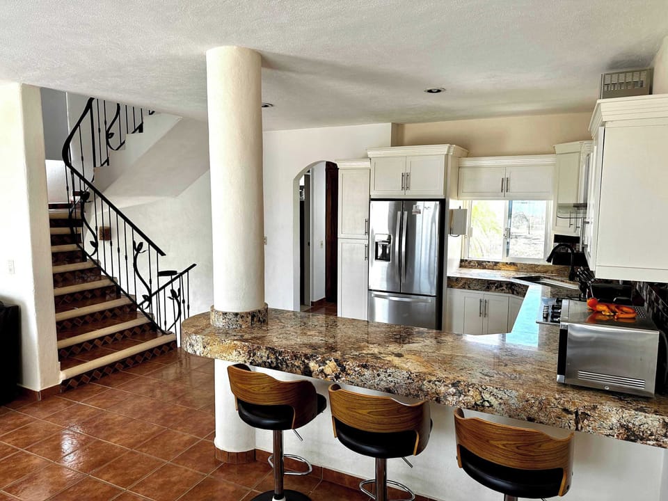 Main house kitchen with bar seating and stairs to rooftop deck.