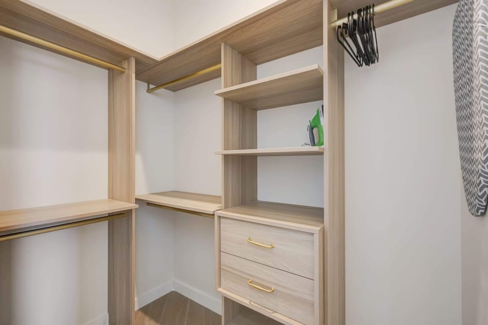 Organize your belongings with ease in this spacious walk-in closet, complete with shelving and an ironing station.
