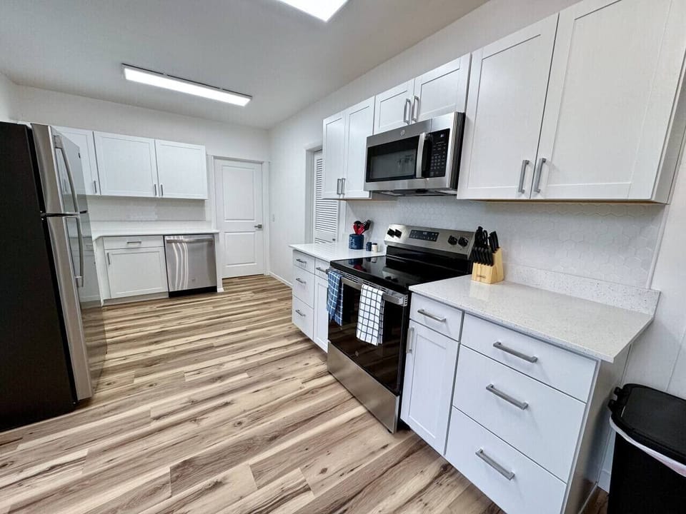 The kitchen with an oven, microwave, fridge, knife set, and kitchen utensils