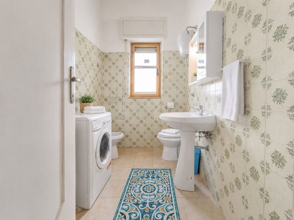 Bright bathroom with washer, natural light, and charming vintage tile