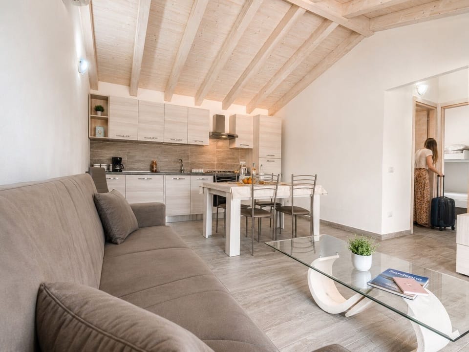 Bright open-plan living space with modern kitchen and warm wood-beamed ceiling