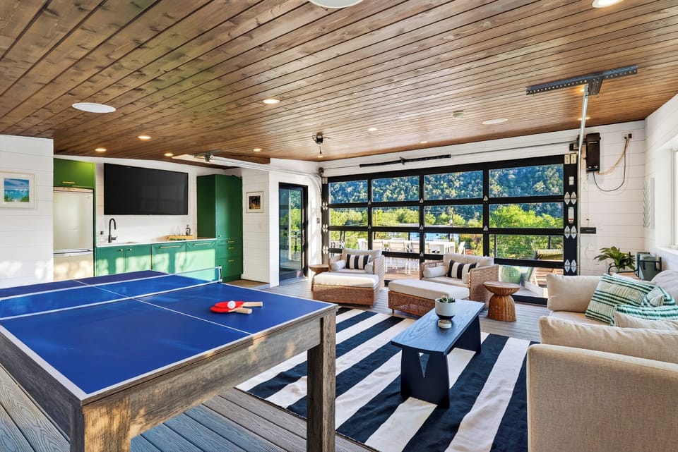 Sunroom game lounge with a game table and hill country views