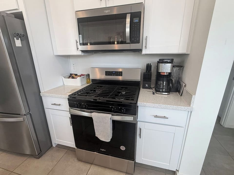 Kitchen stove area with microwave, coffee maker, and cabinets