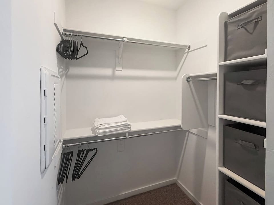 Walk-in closet with shelves, rods, hangers, and folded towels