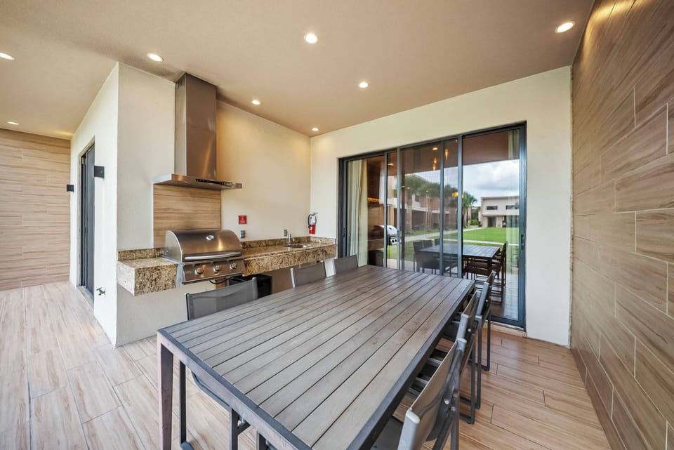 Step into this stylish outdoor dining area, where a sleek wooden table invites you to gather with friends or family. The modern grill and warm lighting create a welcoming atmosphere, perfect for enjoying meals under the open sky.