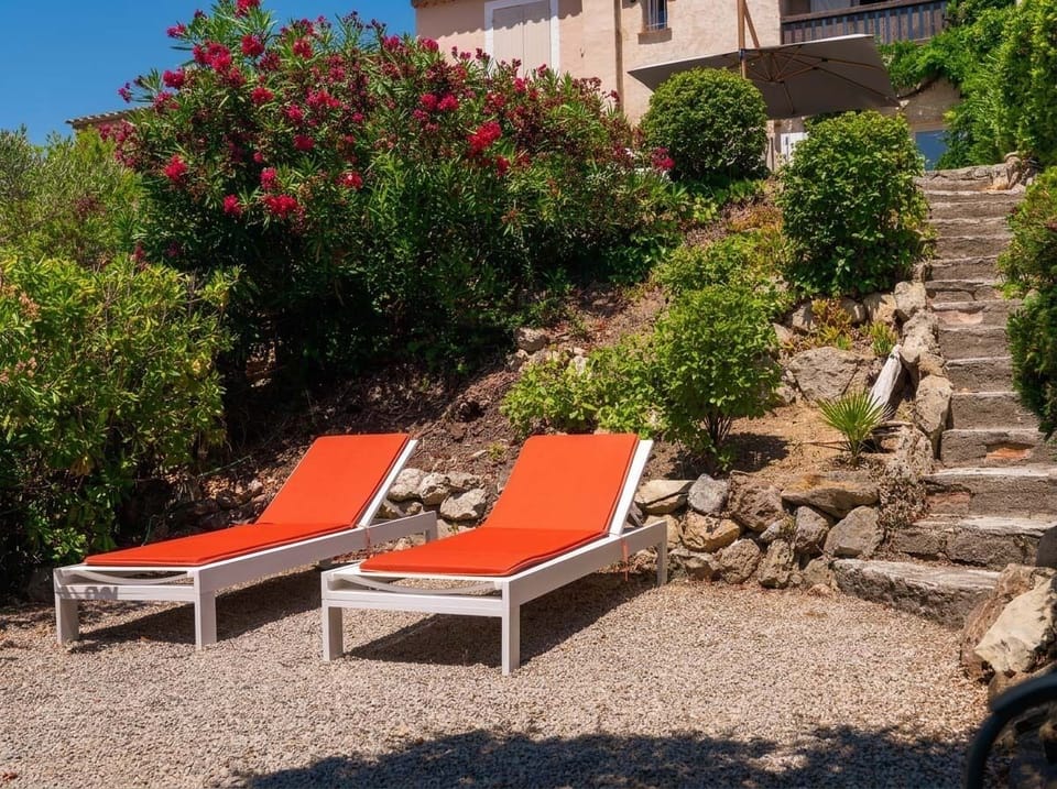 Sunny garden terrace with bright loungers and lush hillside views
