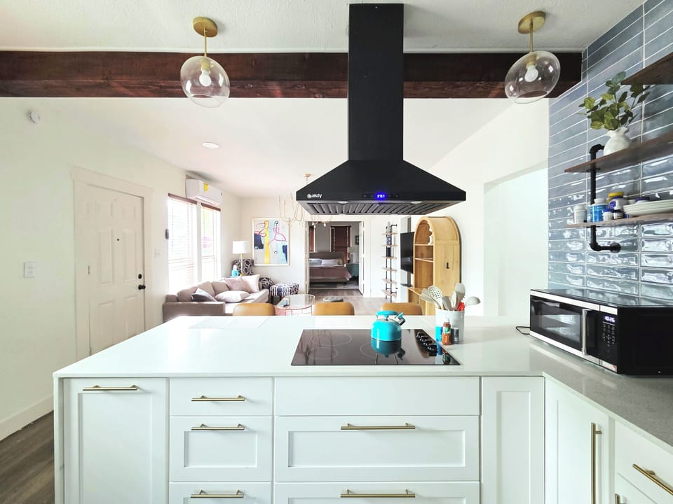 Bright open kitchen with oversized island, stylish range hood, and airy layout