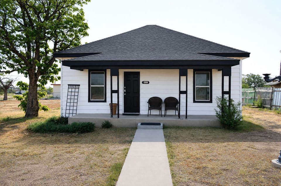 Charming cottage with covered porch, patio seating, and stylish curb appeal
