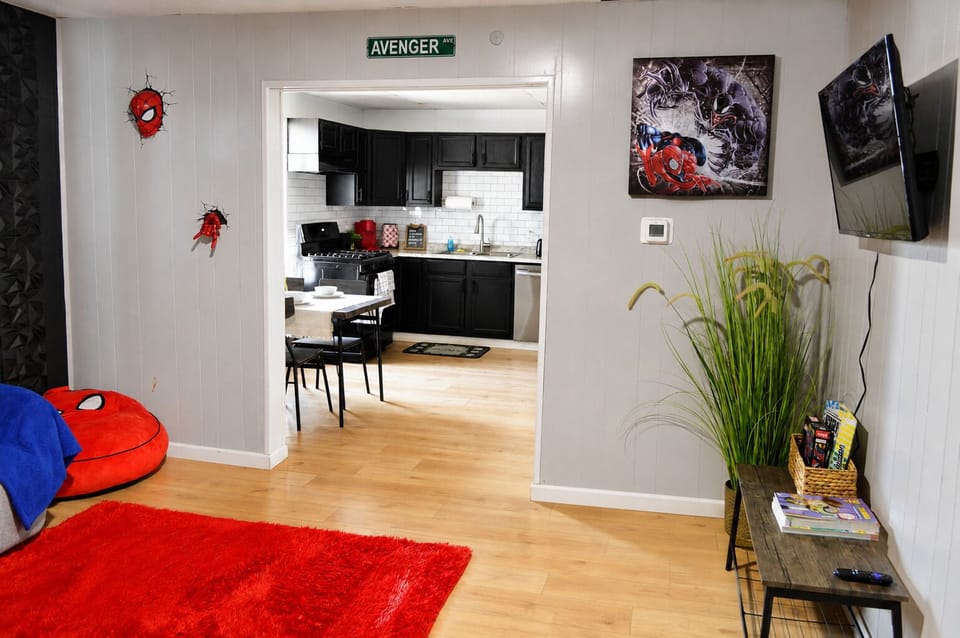 Marvel-themed lounge with TV and sleek kitchen view