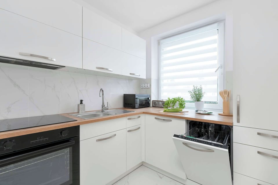 Another perspective of the kitchen emphasizes the clean cabinetry, integrated oven, and bright window above the sink. The layout is efficient and well organized.
