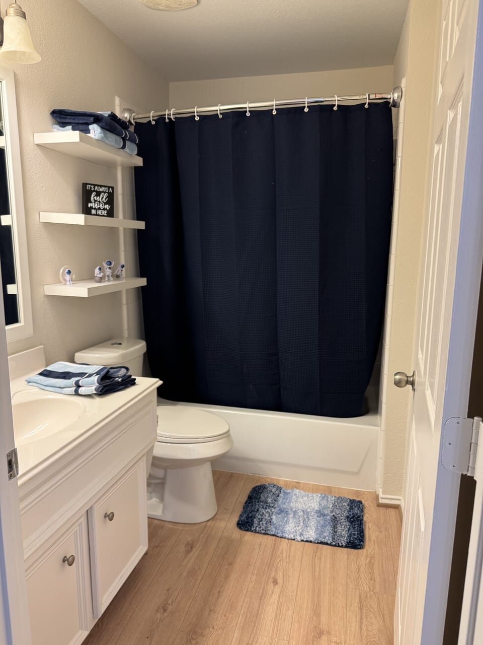 Fresh navy-accent bathroom with tub/shower, plush towels, and essentials