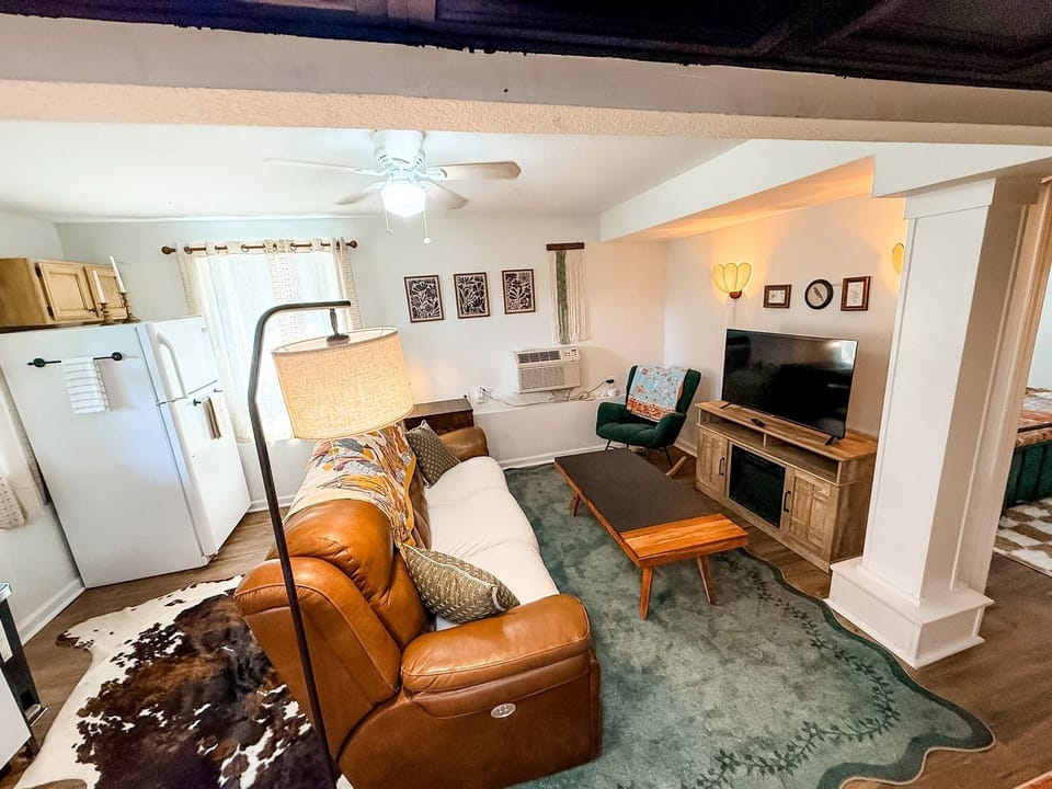 Cozy rustic living room with TV, comfy seating, and open kitchen access