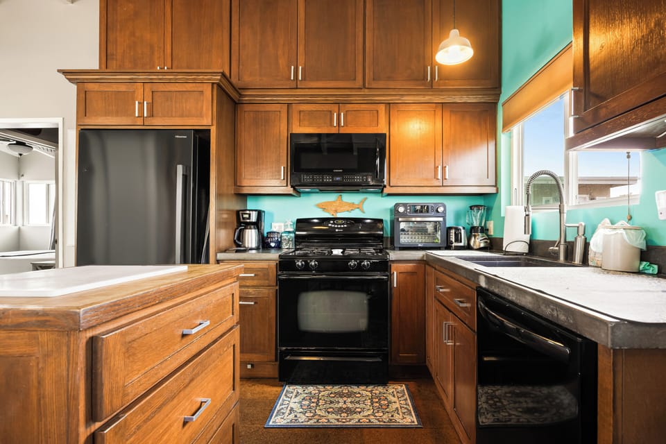 Modern appliances, warm wood cabinetry, vibrant teal accent walls, and ample counter space for preparing meals.
