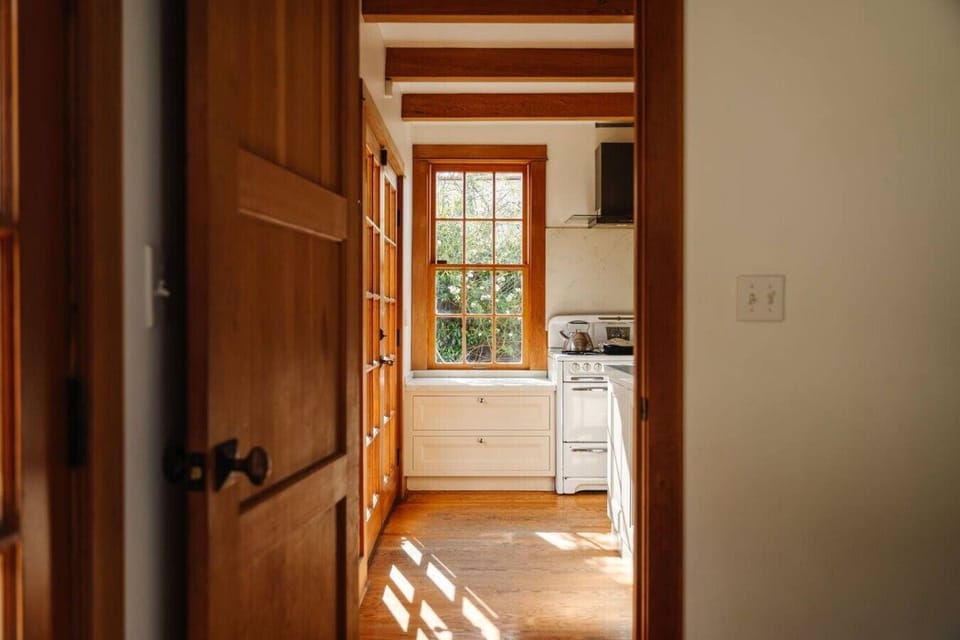 Bright kitchen entry with crisp white cabinetry, rich wood accents, and a sun-filled window — classic character meets everyday function.