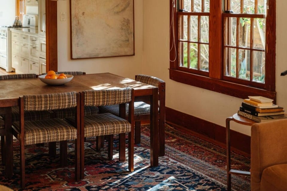 Bright dining space with a classic wood table, natural light streaming through vintage windows — perfect for morning coffee or evening meals.