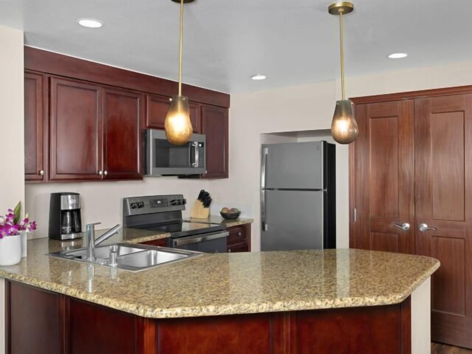 Modern kitchen with granite island, stainless appliances, and warm wood cabinetry