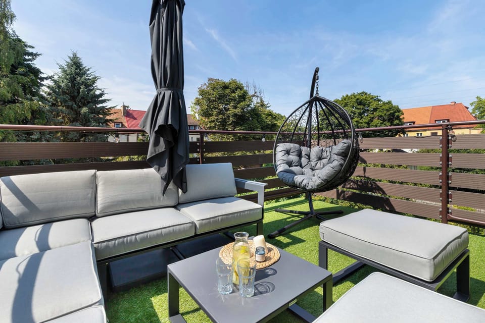 The terrace offers stylish outdoor seating with a coffee table and hanging chair overlooking the surrounding neighborhood. It provides an ideal setting for relaxing outdoors.