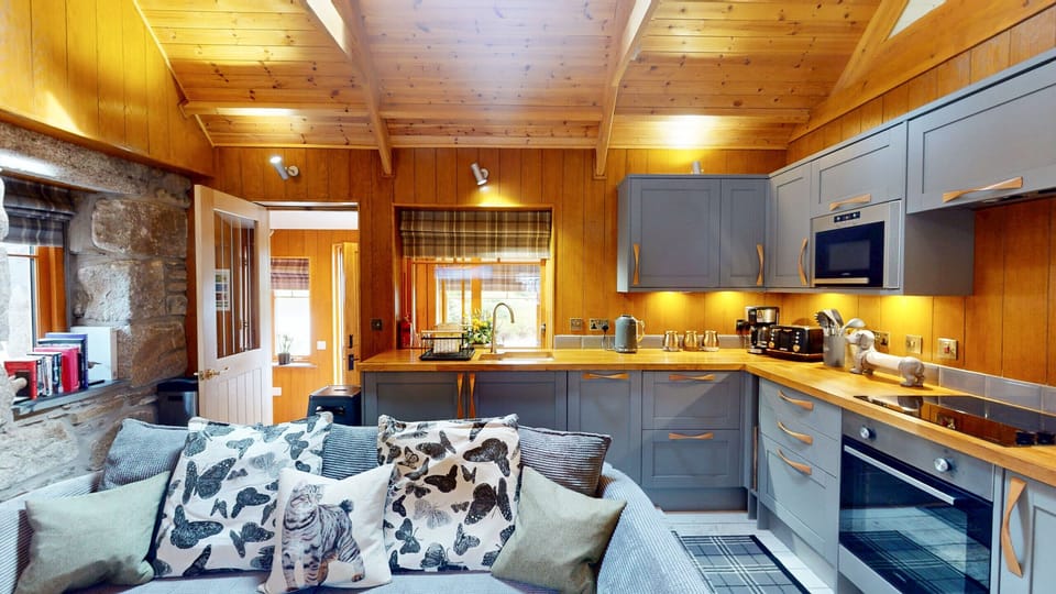 Curl up on the sofa and you're still part of whatever's happening at the stove. Soft cushions, stone walls and a pine ceiling overhead.