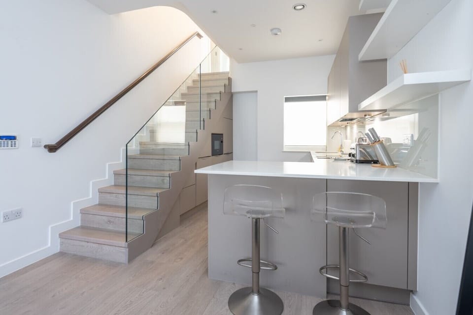 Modern kitchen with quartz island, bar seating and glass staircase