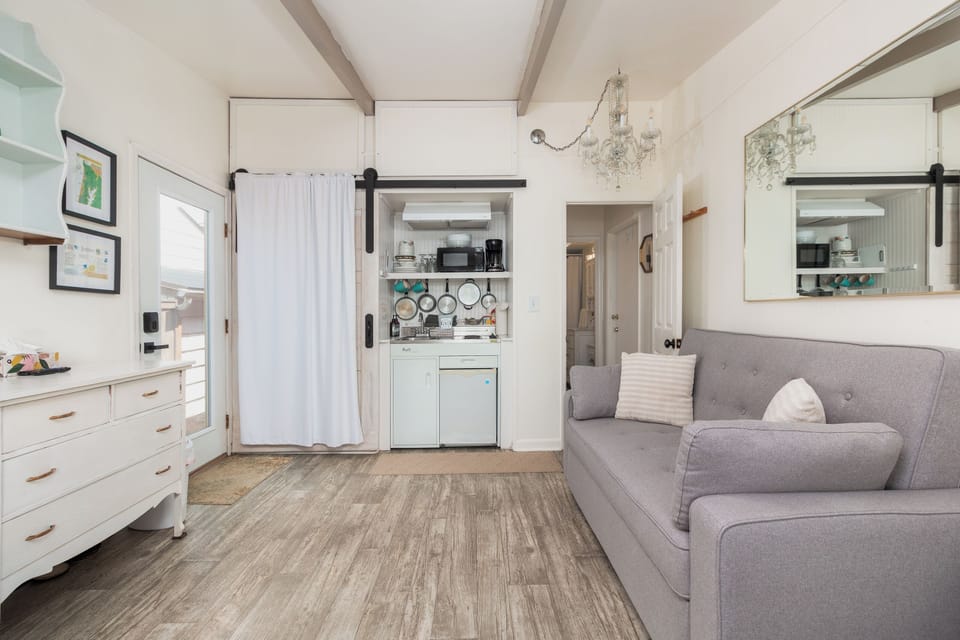 Unwind in your bright, open living space with soaring ceilings and elegant chandelier lighting. Your cozy kitchenette awaits behind charming barn doors, while plush seating invites you to relax.