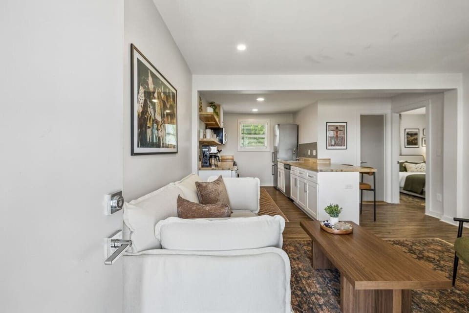 Cozy living room with a Smart TV and comfortable furnishings for you to relax. Open concept area leading into the kitchen, dining high top, and washer/dryer area.