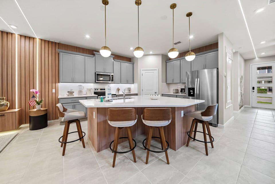 Discover a stylish kitchen with warm wood accents and sleek gray cabinetry, perfect for gatherings around the spacious island. Enjoy modern appliances and ample counter space, all enhanced by elegant pendant lighting for a.