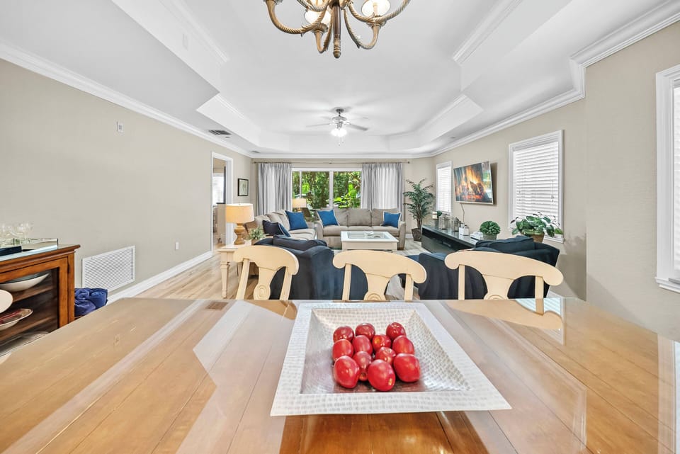 Enjoy the spacious dining area filled with natural light that showcases the warm wood tones of the inviting table and stylish chairs, complemented by an elegant coffered ceiling and vibrant decor for an uplifting atmosphere.