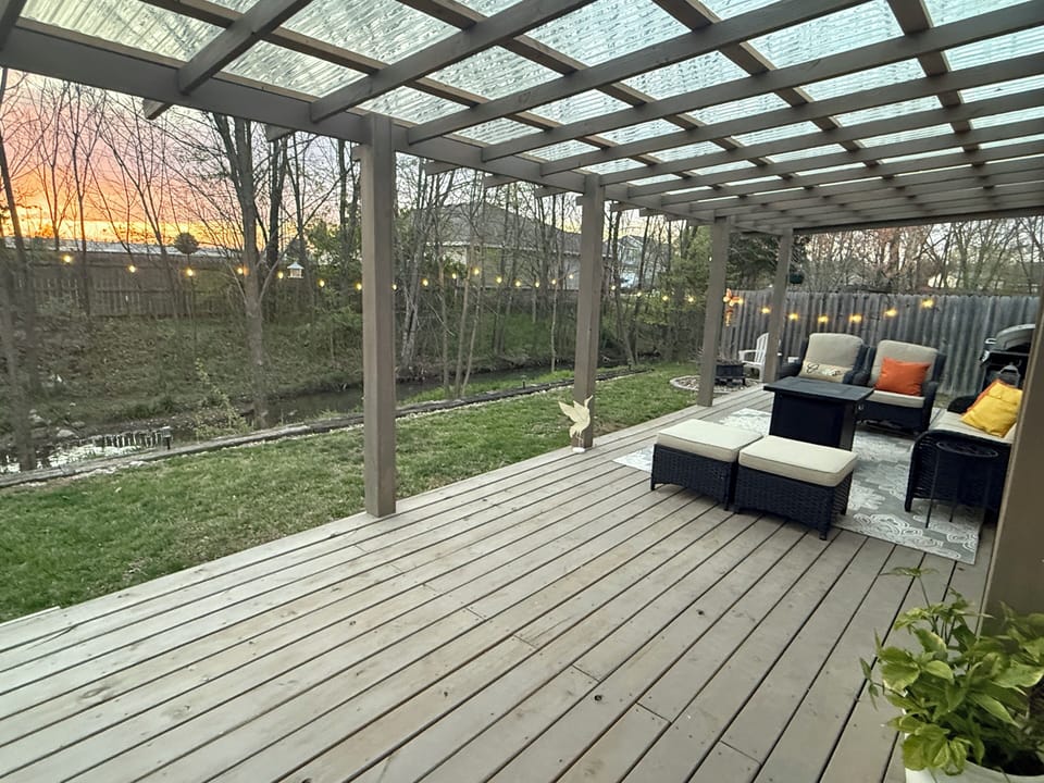 Covered creekside deck with comfortable seating, string lights and sunset views.