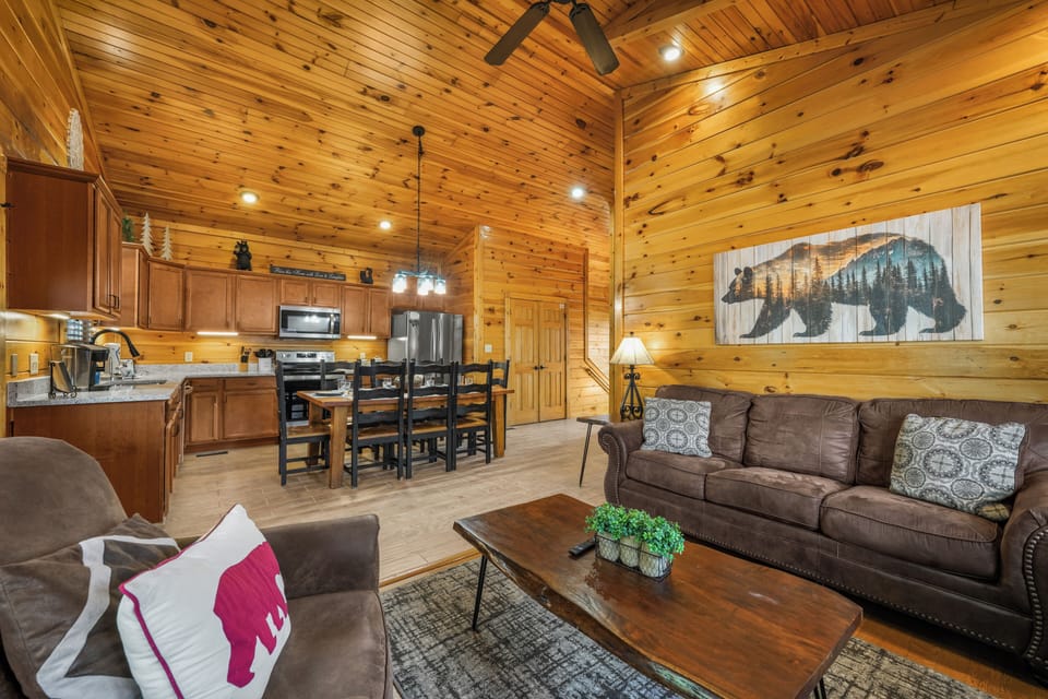 Cozy cabin great room with vaulted wood ceilings, full kitchen, and dining area