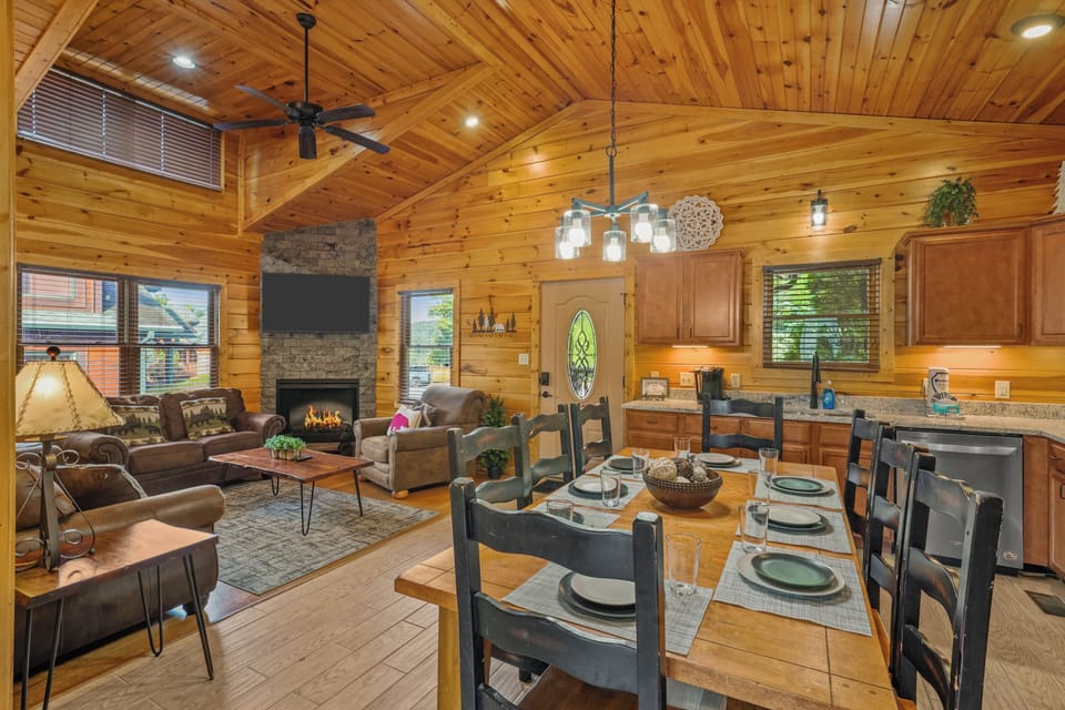 Cozy open-concept cabin with fireplace, dining for 8, and warm wood interiors