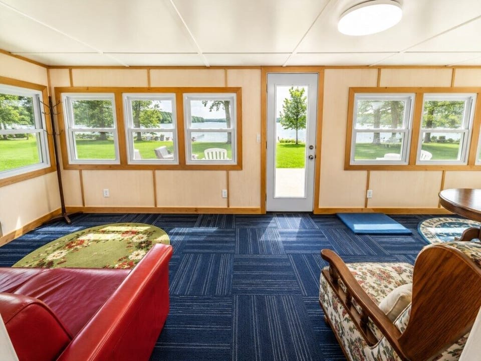 Sun porch with two sofas, a rocking chair, a game table, expansive lake views, and a door leading to the deck.